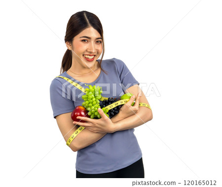 Young asian woman in fitness clothes holding fruits with measuring tape. Portrait on white background with studio light. Healthy nutrition and weight losing concept. Young asian woman in fitness clothes holding fruits with measuring tape. Portrait on white background with studio light. Healthy nutrition and weight losing concept. 120165012