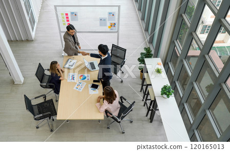 A group of business professional are in an office, engaging in a firm handshake following a successful meeting or agreement. A group of business professional are in an office, engaging in a firm handshake following a successful meeting or agreement. 120165013