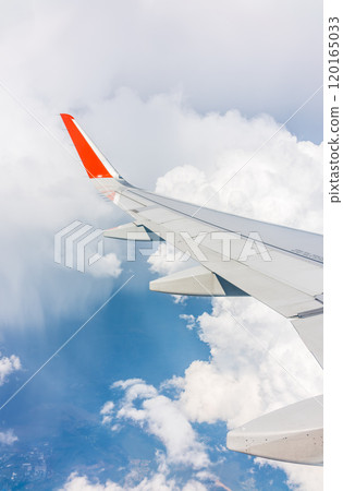 View from the airplane window at a beautiful cloudy sky and the airplane wing 120165033
