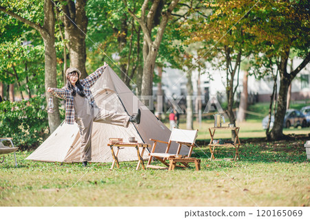 A young woman having fun in front of a tent 120165069