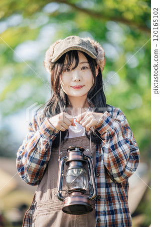 Young woman holding a lantern in front of a tent 120165102