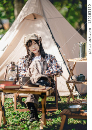Young woman sitting in front of a tent 120165150