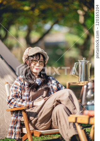 Young woman wearing sunglasses sitting in front of a tent Young woman wearing sunglasses sitting in front of a tent 120165204