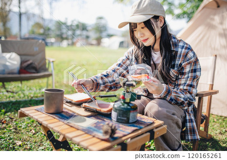 Young woman preparing lunch for camping Young woman preparing lunch for camping 120165261