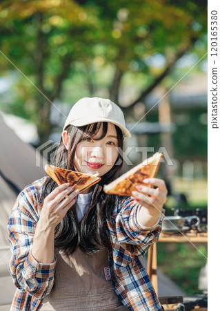 Woman eating at a campsite 120165380