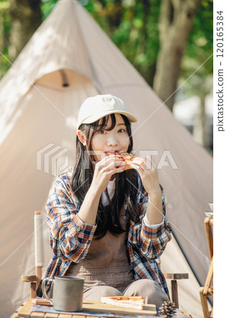 Woman eating at a campsite Woman eating at a campsite 120165384