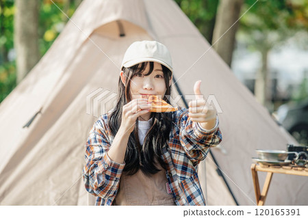 Woman eating at a campsite 120165391