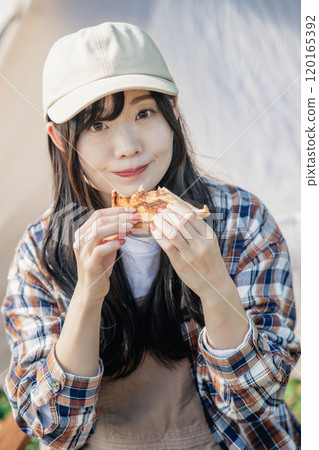 Woman eating at a campsite Woman eating at a campsite 120165392