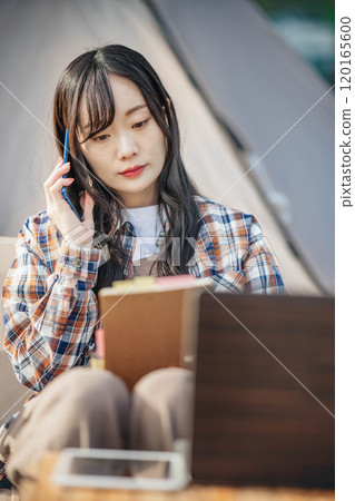 Young woman working at a campsite Young woman working at a campsite 120165600