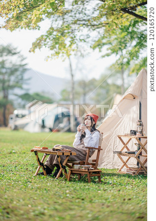 A woman taking a break at a campsite while eating and drinking A woman taking a break at a campsite while eating and drinking 120165720