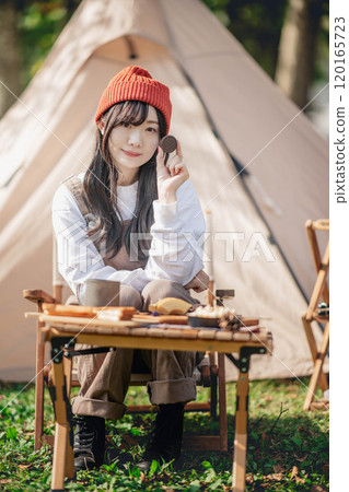 A woman taking a break at a campsite while eating and drinking A woman taking a break at a campsite while eating and drinking 120165723