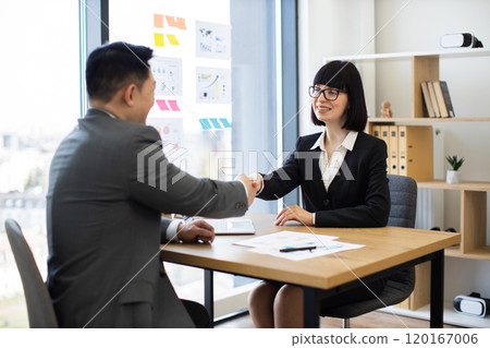 Caucasian businesswoman shakes hands with Asian businessman after agreement Caucasian businesswoman shakes hands with Asian businessman after agreement 120167006