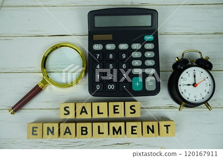Sales Enablment with wooden blocks alphabet letters and magnifying glass, calculator, alarm clock top view on wooden background 120167911