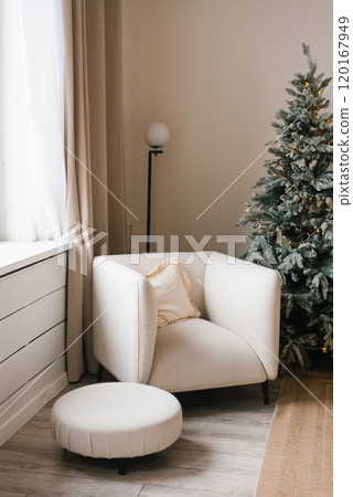 White armchair and ottoman are in front of a Christmas tree at living room White armchair and ottoman are in front of a Christmas tree at living room 120167949