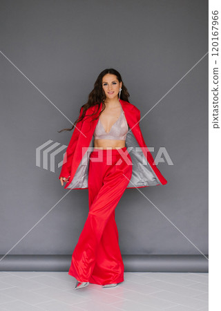 Caucasian young woman in red suit and pants poses for photo. Concept of confidence and sophistication 120167966