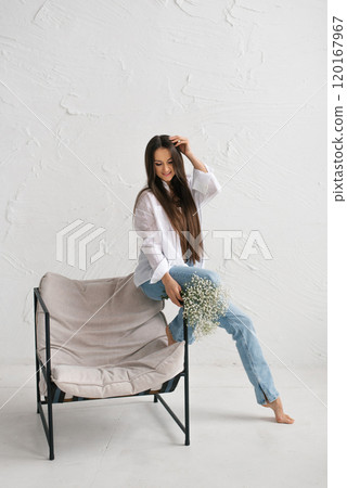 Happy woman sits in a chair with a bouquet of flowers in her lap 120167967