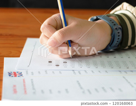 hand holding pencil over bubble answer sheet 120168063