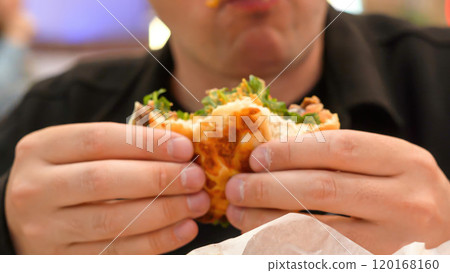 Man eating veggie burger in a vegan cafe or restaurant.  120168160