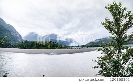 River with cloud covered green mountains in the background 120168301