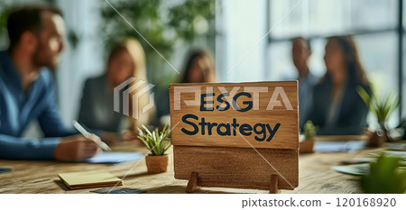 A team discussing ESG strategy with a sign on the table, surrounded by colleagues and greenery, showcasing collaboration and sustainability in a modern workspace. 120168920