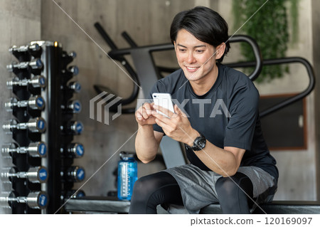Gym/Training Young Asian man watching training videos on his smartphone at the gym (online fitness) Gym/Training Young Asian man watching training videos on his smartphone at the gym (online fitness) 120169097
