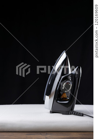 熨衣板上放置的熨斗和黑色背景上的複製空間 120169609