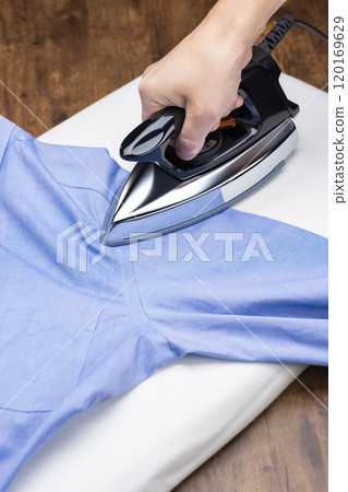 Close-up of a man's hands ironing a shirt 120169629