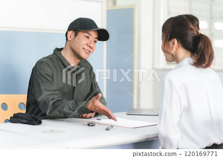 A male mechanic and a female customer giving explanations, estimates and proposals at the reception desk of an auto repair shop A male mechanic and a female customer giving explanations, estimates and proposals at the reception desk of an auto repair shop 120169771