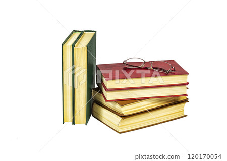 On the white surface is a pile of hard-bound books and reading glasses 120170054