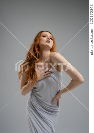 Elegant woman posing in soft gray wrap dress against a neutral background Elegant woman posing in soft gray wrap dress against a neutral background 120170348