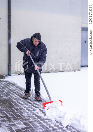 Selective focus man shoveling snow on driveway during winter in cold weather with red shovel. World Snow Day. Snowstorm and natural disasters and snowfalls 120171053
