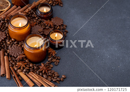 Soy scented candle in a jar. Coffee beans, anise, cinnamon spices. The candles are burning. Dark copy space background. Soy scented candle in a jar. Coffee beans, anise, cinnamon spices. The candles are burning. Dark copy space background. 120171725
