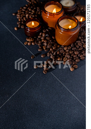 Soy scented candle in a jar. Coffee beans, anise, cinnamon spices. The candles are burning. Dark copy space background. Soy scented candle in a jar. Coffee beans, anise, cinnamon spices. The candles are burning. Dark copy space background. 120171785