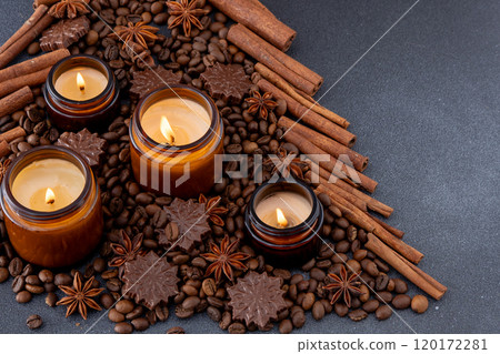 Soy scented candle in a jar. Coffee beans, anise, cinnamon spices. The candles are burning. Dark background. Soy scented candle in a jar. Coffee beans, anise, cinnamon spices. The candles are burning. Dark background. 120172281