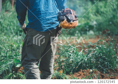 一名男子用引擎驅動的割灌機割草 120172545