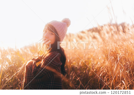 A woman surrounded by silver grass dyed in the sunset 120172851