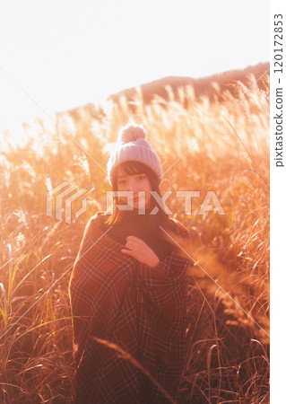 一個女人被夕陽染上的潘帕斯草包圍 120172853