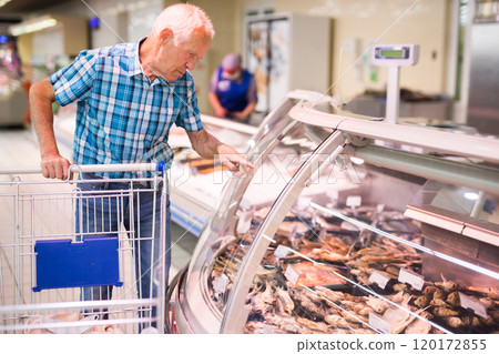 Mature senor choosing dried fish in supermarket Mature senor choosing dried fish in supermarket 120172855