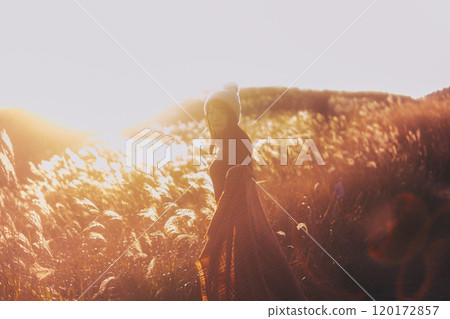 一個女人被夕陽染上的潘帕斯草包圍 120172857
