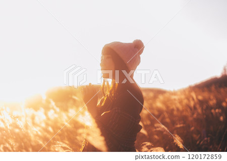 一個女人被夕陽染上的潘帕斯草包圍 120172859