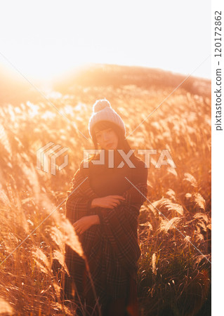 A woman surrounded by silver grass dyed in the sunset A woman surrounded by silver grass dyed in the sunset 120172862