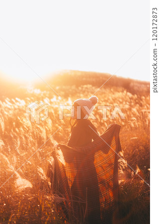 一個女人被夕陽染上的潘帕斯草包圍 120172873