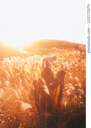 一個女人被夕陽染上的潘帕斯草包圍 120172874