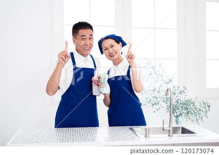 穿著藍色圍裙和白色 Polo 衫的高級管家（男性和女性、丈夫和妻子）在廚房排隊 120173074