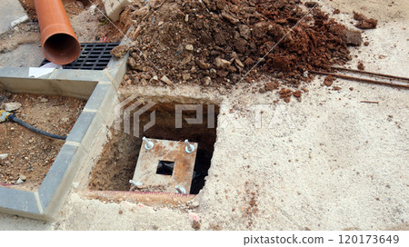 Workers laying communication lines on a construction site with open trenches and equipment in progress during daylight hours 120173649