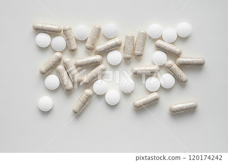 Assorted pills and vitamin capsules on plain background, symbolizing health and wellness. 120174242
