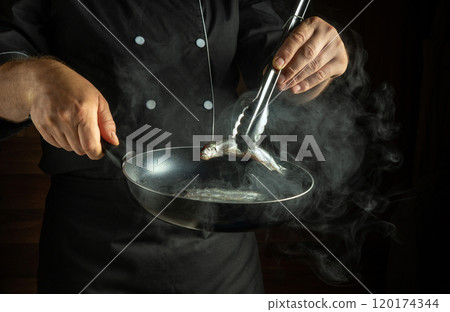 A chef expertly handles a piece of fresh fish in a frying pan, with steam rising in the warm ambiance of a dimly lit kitchen, preparing a delicious dinner A chef expertly handles a piece of fresh fish in a frying pan, with steam rising in the warm ambiance of a dimly lit kitchen, preparing a delicious dinner 120174344