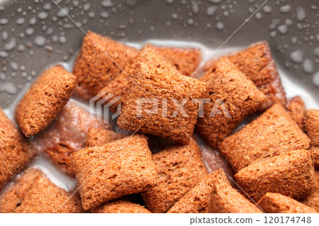 Brown cereal chocolate pillows in milk with bubbles on the surface, capturing a satisfying breakfast scene with contrasting textures and creamy appeal. Top View 120174748
