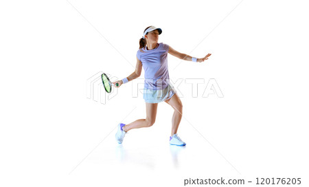 Focused on game, female tennis athlete swinging racket, ready to backhand and make powerful hit against white studio background. 120176205