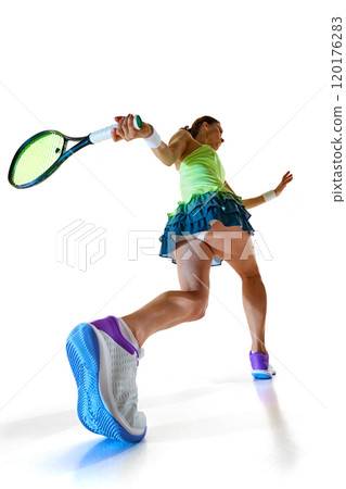 Rear view of athlete, with her racket swung back, embodies focus and precision, ready to unleash powerful strike against white studio background. 120176283